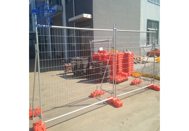 Galvanized wire mesh temporary construction fence with orange plastic base installed for road site safety